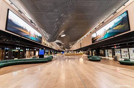 Interior de la Terminal 3 del aeropuerto de Frankfurt con grandes pantallas LED de LG Electronics instaladas en el techo del área Market Place mostrando imágenes de paisajes naturales