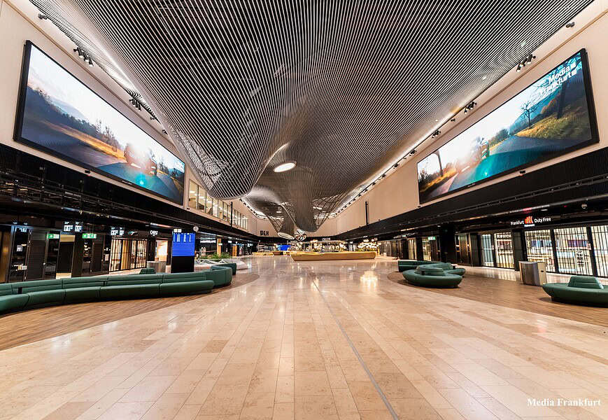 Interior de la Terminal 3 del aeropuerto de Frankfurt con grandes pantallas LED de LG Electronics instaladas en el techo del área Market Place mostrando imágenes de paisajes naturales