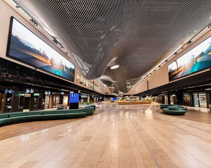 Interior de la Terminal 3 del aeropuerto de Frankfurt con grandes pantallas LED de LG Electronics instaladas en el techo del área Market Place mostrando imágenes de paisajes naturales