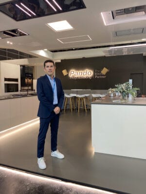 Sergio Seña, nuevo director general de Pando Integral Cooking, posando en traje azul marino en el showroom de la compañía con el logo iluminado al fondo