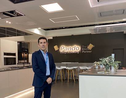 Sergio Seña, nuevo director general de Pando Integral Cooking, posando en traje azul marino en el showroom de la compañía con el logo iluminado al fondo