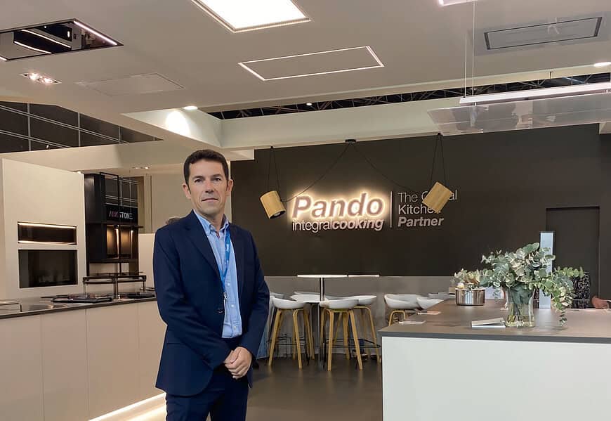 Sergio Seña, nuevo director general de Pando Integral Cooking, posando en traje azul marino en el showroom de la compañía con el logo iluminado al fondo