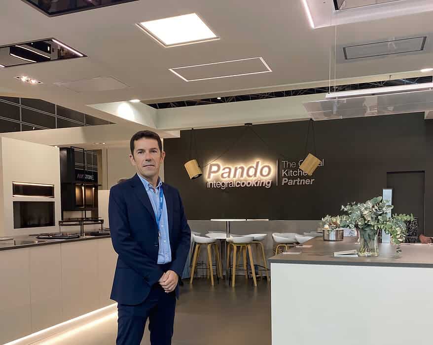 Sergio Seña, nuevo director general de Pando Integral Cooking, posando en traje azul marino en el showroom de la compañía con el logo iluminado al fondo
